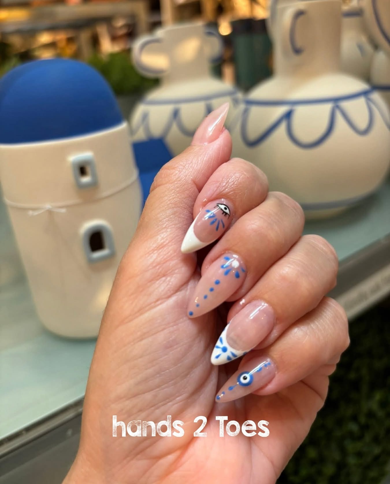 Nude stiletto nails with blue evil eye nail art